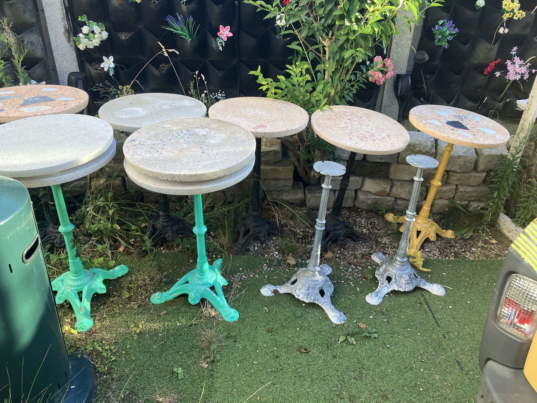 Les tables en terrazzo alignées dans le jardin de l'atelier : pieds verts, argentés, jaune et noirs